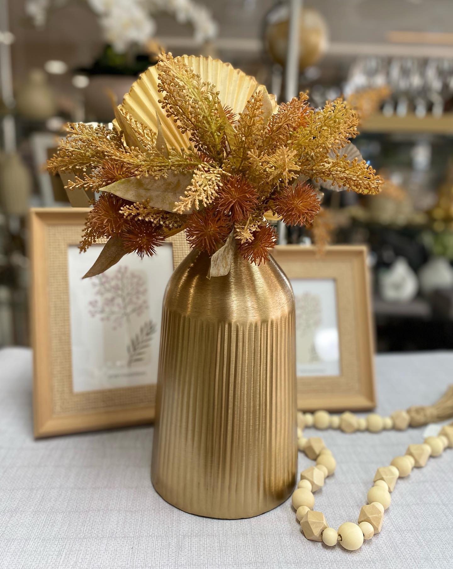 Vaso dourado com flores secas âmbar